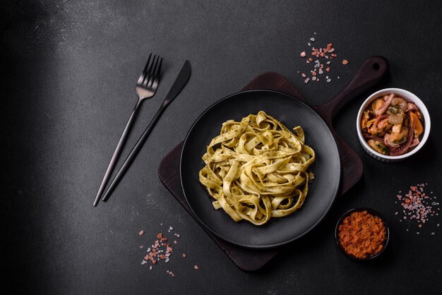 Heerlijke verse pasta met pestosaus en zeevruchten op een zwarte plaat