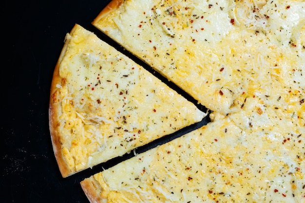 Heerlijke vier kazen pizza met cheddar, parmezaanse kaas, mozzarella en tomatensaus op een zwarte achtergrond. uitzicht van boven.