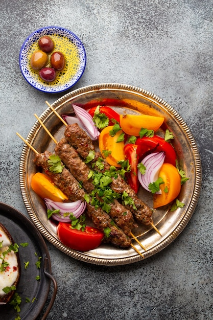 Heerlijke vleeskebab met verse groentesalade geserveerd op rustieke plaat, traditionele midden-oosterse schotel. lekkere en gezonde maaltijd uit de arabische of mediterrane keuken, van bovenaf