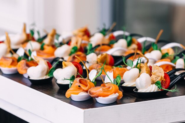 Heerlijke voorgerechten op huwelijkslepels met kaas en rode vis zijn versierd met tomaten