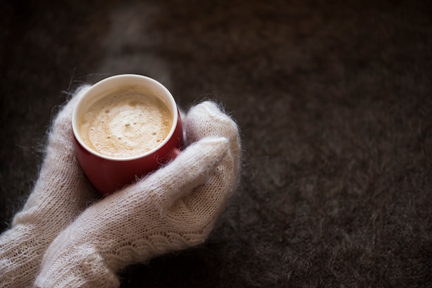 Heerlijke warme koffie in de rode cirkel in de winter koud in de handen van meisje in gebreide handschoenen