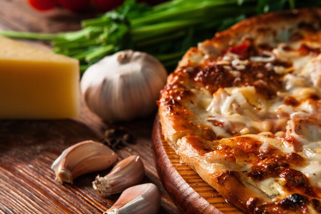 Heerlijke warme pizza gesneden en geserveerd op houten tafel met ingrediënten close-up weergave.