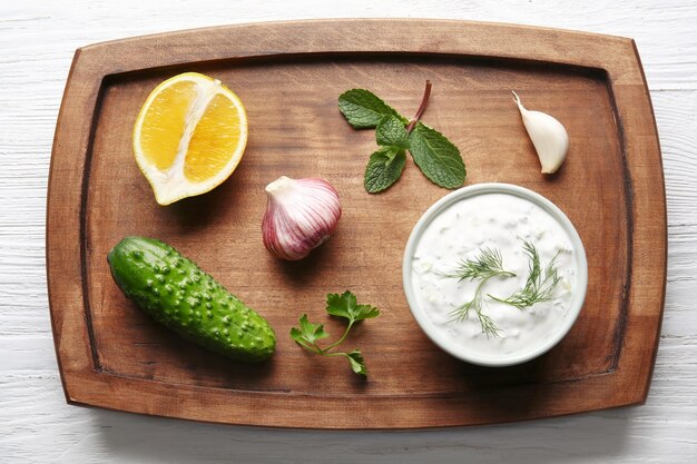 Heerlijke yoghurtsaus in een kom met ingrediënten op een houten plank