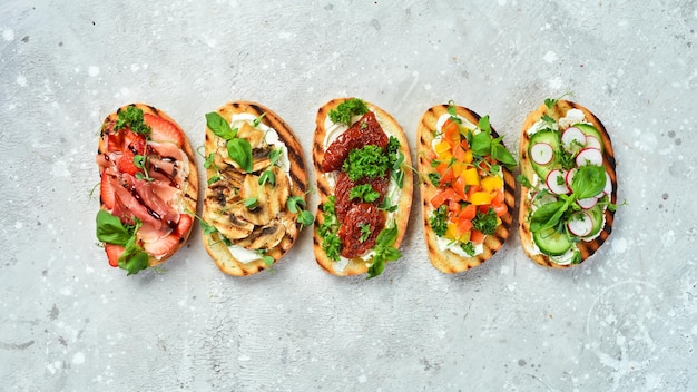 Heerlijke zelfgemaakte bruschetta's met groenten, kaas, champignons en prosciutto Sandwich op een stenen achtergrond Bovenaanzicht