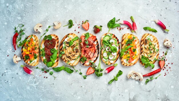 Heerlijke zelfgemaakte bruschetta's met groenten, kaas, champignons en prosciutto Sandwich op een stenen achtergrond Bovenaanzicht