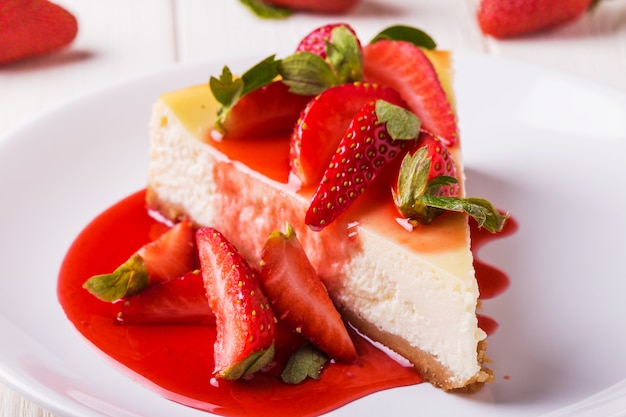 Heerlijke zelfgemaakte cheesecake met aardbeien op witte houten tafel.