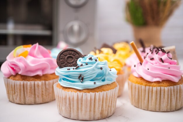 Heerlijke zelfgemaakte cupcakes met kleurrijke slagroom en topping met snoep en chocoladekoekjes. huisgemaakt herfstvakantiedessert