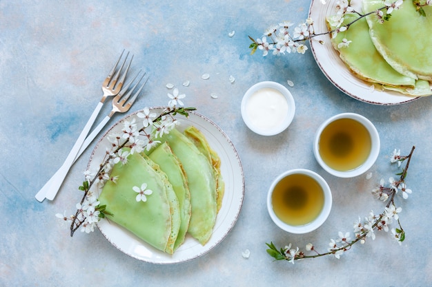 Heerlijke zelfgemaakte groene pannenkoeken met bloeiende kersenboom takken met groene thee