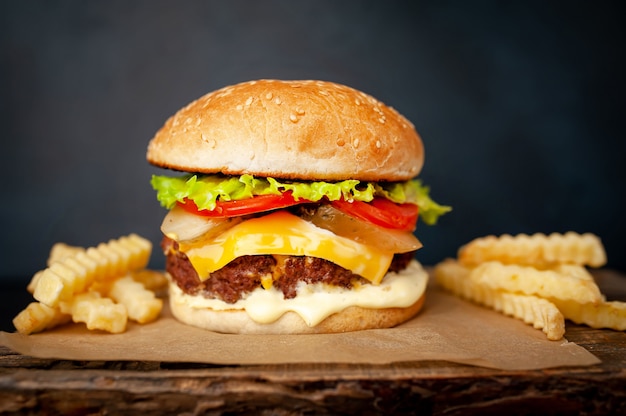 Heerlijke zelfgemaakte hamburger met rundvlees, sla, kaas, komkommer en frietjes op stenen achtergrond