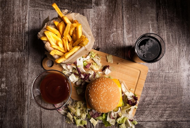 Heerlijke zelfgemaakte hamburgers op houten bord naast friet en cola. Fast food. Ongezond tussendoortje