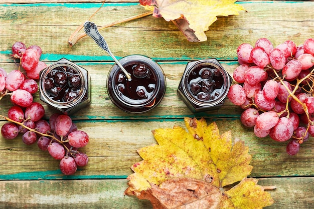 Heerlijke zelfgemaakte herfstdruivenjam op oude houten achtergrond. Pot met bessenjam