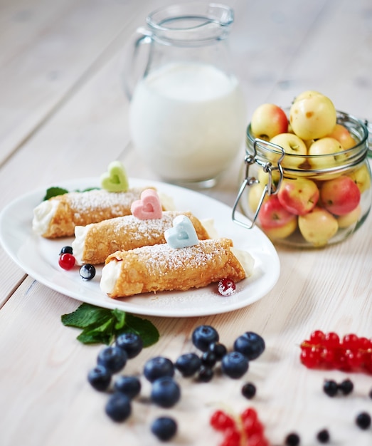 Heerlijke zoete cannoli met bessen op een houten tafel.