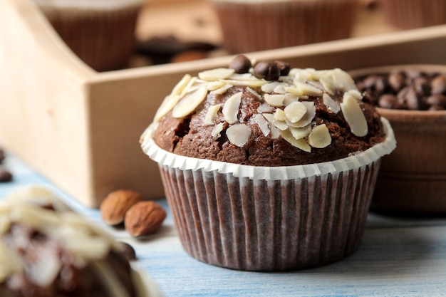 Heerlijke, zoete chocolademuffins, met amandelbloemblaadjes naast de koffiebonen op een blauwe houten tafel.