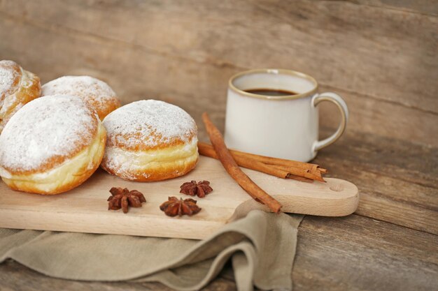 Heerlijke zoete donuts met kruiden en kopje koffie op houten ondergrond