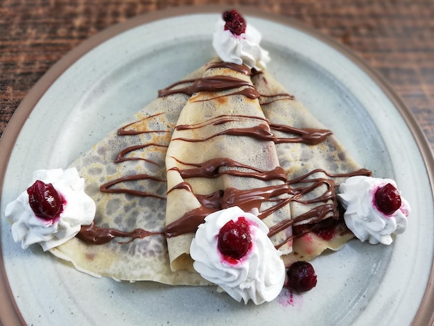 Foto heerlijke zoete pannenkoeken bedekt met chocoladereep en kersen