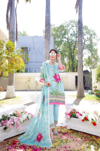 Heet prachtig meisje vooraan poseren met Desi-jurkjuwelen en zonnebril in de tuin