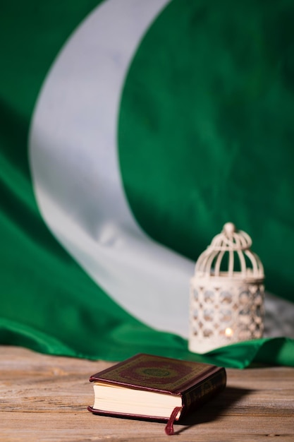 Heilig boek van de koran op een houten oppervlak vlag van pakistan en kandelaar op de achtergrond vertaalboek bevat verzen uit de koran