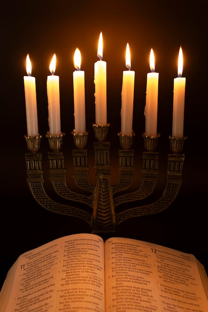 Foto heilige bijbel geopend op het boek van jesaja in hoofdstuk 11 en menorah met 7 aangestoken kaarsen