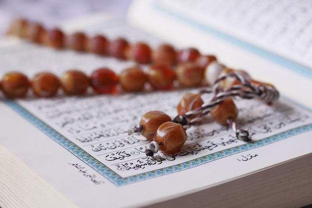 Heilige boek Koran en rozenkrans op tafel, close-up.