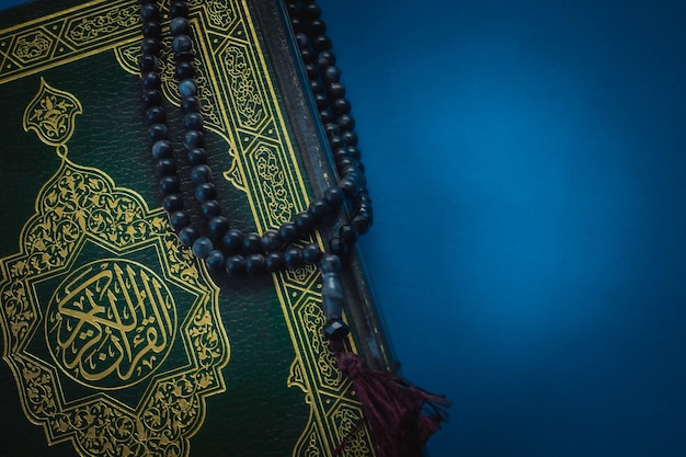 Heilige Koran met Arabische kalligrafie betekenis van Al Quran en tasbih of rozenkrans kralen op zwarte achtergrond Selectieve focus en kopieer ruimte