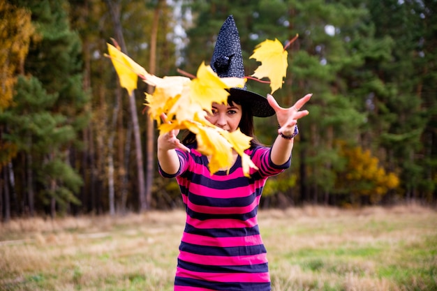 Foto heks gooit bladeren in het herfstbos halloween kostuumfeest goochelaar