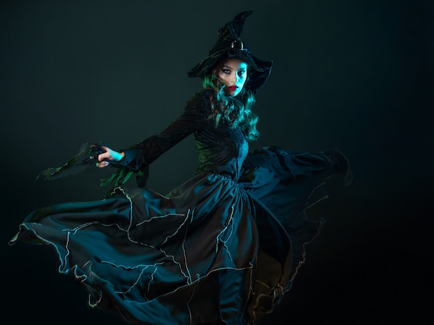 Heks in een lange zwarte jurk die danst en een halloweenfeestje tovert