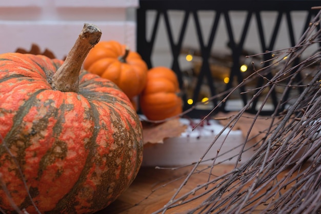 Heksenbezem en oranje pompoenen op bruine bladeren in de buurt van wazige open haard close-up Selectieve focus Herfst Halloween-concept