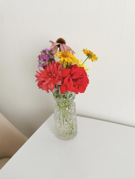 Helder boeket bloemen op tafel in een glazen vaas