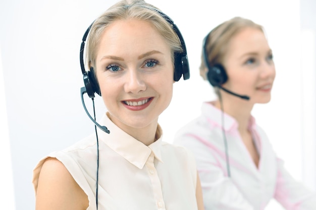 Helder en zonnig callcenter. Groep blonde vrouwen in hoofdtelefoon op het werk. Kantoor en bedrijfsconcept.