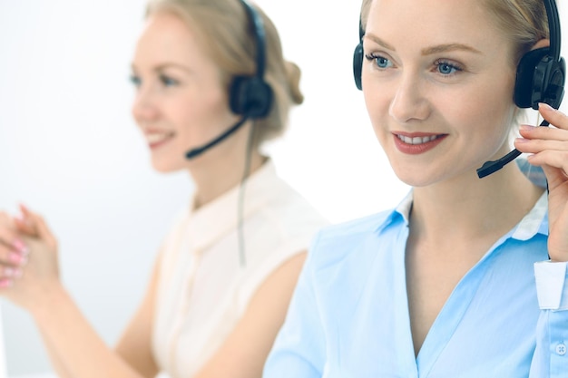 Helder en zonnig callcenter. Groep blonde vrouwen in hoofdtelefoon op het werk. Kantoor en bedrijfsconcept.