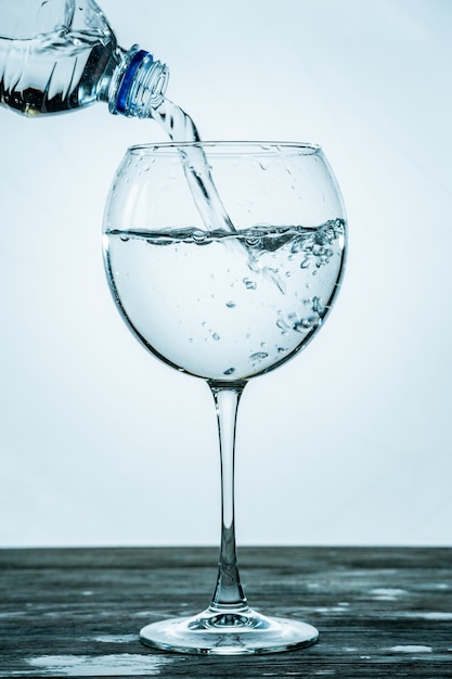 Helder, gezond bruisend water wordt uit een fles in een transparant glas gegoten