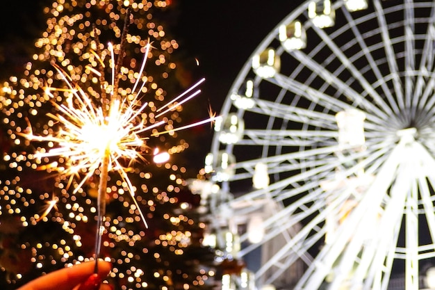 Helder sterretje tegen nieuwjaars feestelijke kerstboomlichten en reuzenrad in nachtstad