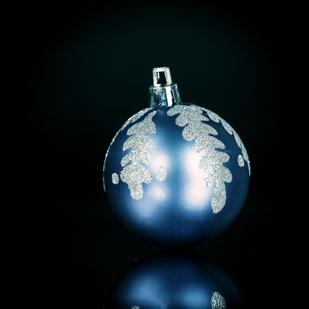 Helderblauwe kerstbal op een zwarte achtergrond