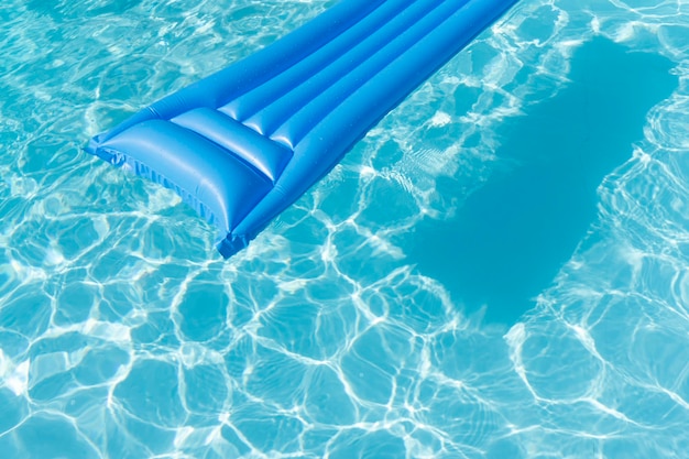 Helderblauwe ligstoel voor het zomerzwembad drijft op een golvend zwembad