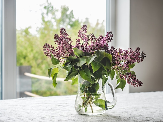 Heldere bloemen in een vaas tegen de achtergrond van het raam