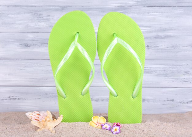 Heldere flipflops op zand op houten achtergrond