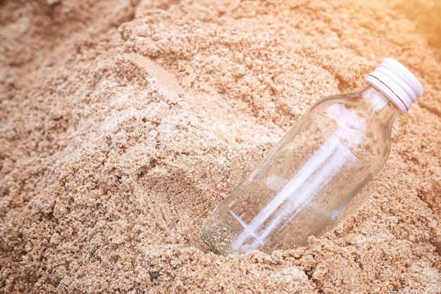 Heldere glazen flessen op het zand op het strand die dag, het concept van milieubescherming