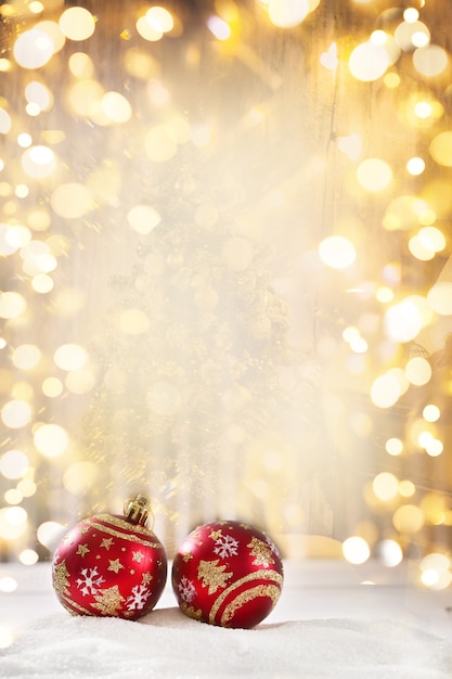 Heldere kerstballen in de sneeuw op een gouden achtergrond met bokeh en vallende sneeuw