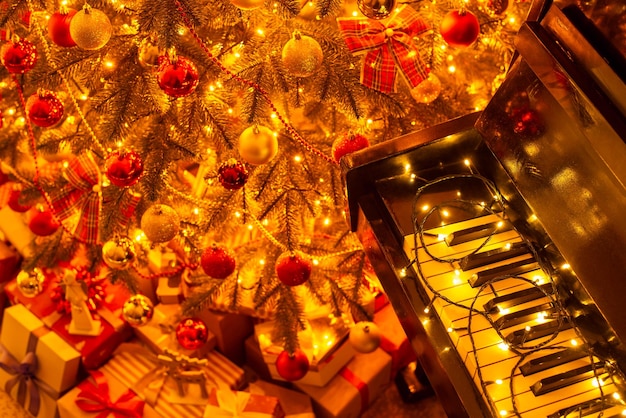 Heldere kerstboom veel cadeautjes eronder in de buurt van piano Mooie feestelijke kerstcompositie