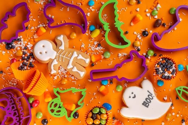 Heldere kleurrijke Halloween-peperkoekkoekjes en zoete achtergrond Zelfgemaakte koekjes met koekjesmessen, suikerhagelslag en snoepjes Hooggekleurde Halloween-traktaties plat lag bovenaanzicht kopieerruimte