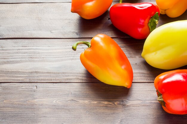 Heldere kleurrijke rijpe paprika op de achtergrond van een houten tafel