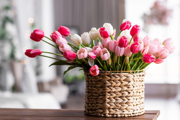 Heldere kleurrijke tulpen in een rieten mand op een houten tafel in de woonkamer