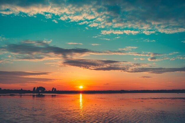 Heldere kleurrijke zonsondergang over rivier Gouden zon