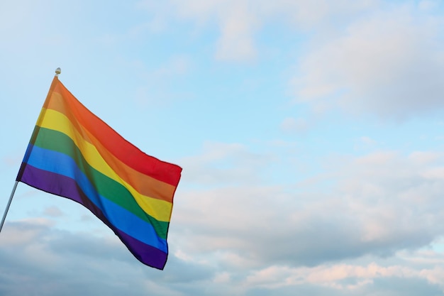 Heldere LGBT-vlag tegen blauwe lucht met wolken Ruimte voor tekst