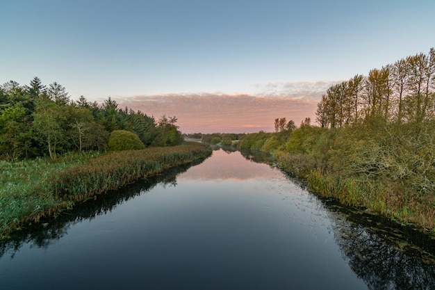 Heldere lucht ochtend op Inny rivier met reflecties van lucht, bomen.