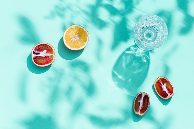 Heldere plakjes citrusvruchten en glas met water op pastel turkoois gekleurd fruitvoedsel en zomerconcept