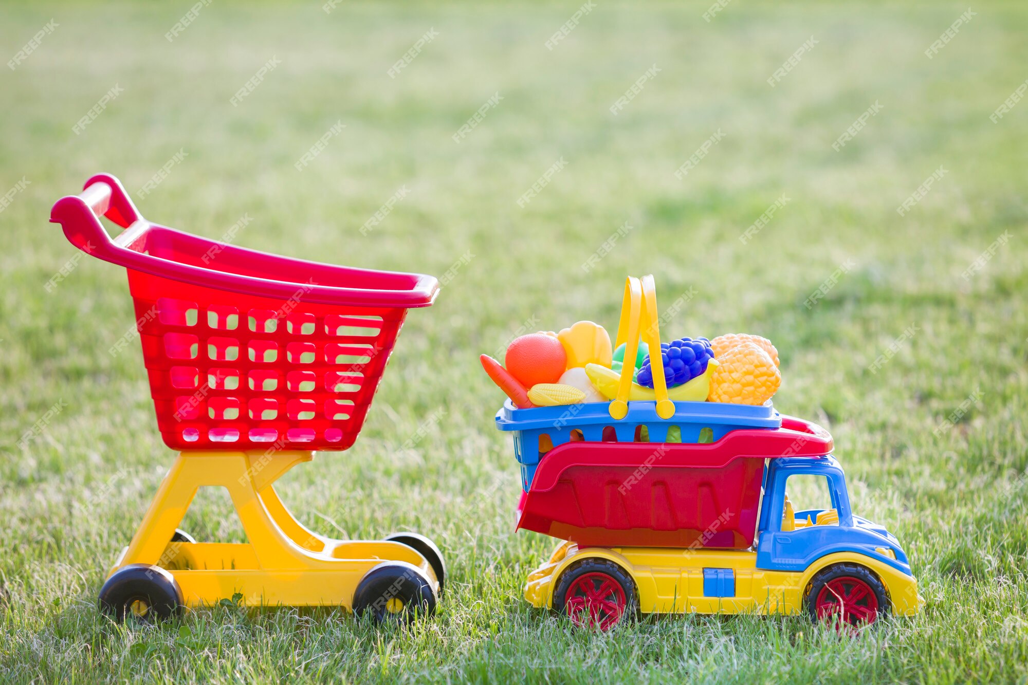 Draak Boren Passief Heldere plastic kleurrijke speelgoed voor kinderen buiten op zonnige  zomerdag. de vrachtwagen dragende mand van de auto met stuk speelgoed  groenten en fruit en het winkelen handkar. | Premium Foto