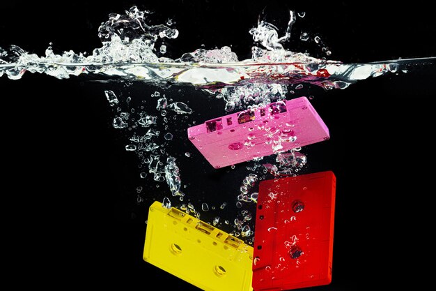 Foto heldere retro audiocassette die in het water tegen zwarte dichte omhooggaand duikt