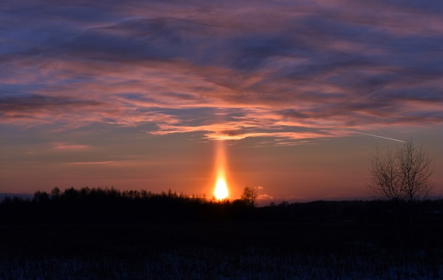 Heldere rode zonsondergang in het winterveld