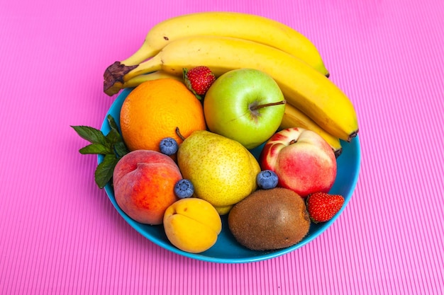 Heldere, sappige vruchten die in een bord liggen - bosbessen, bananen, peren, appels, munt